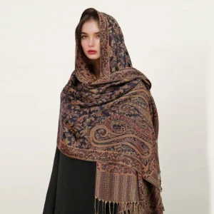 Model wearing dark navy Tibetan paisley shawl with golden brown jacquard patterns and tassel hem, front headshot view