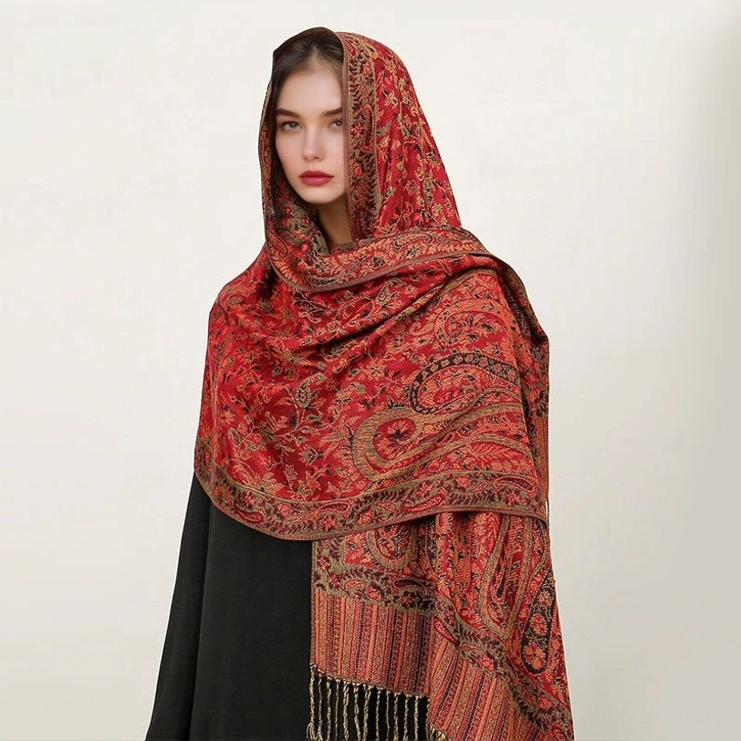 Model wearing red Tibetan paisley shawl with golden brown ethnic patterns and fringed tassel hem, front headshot