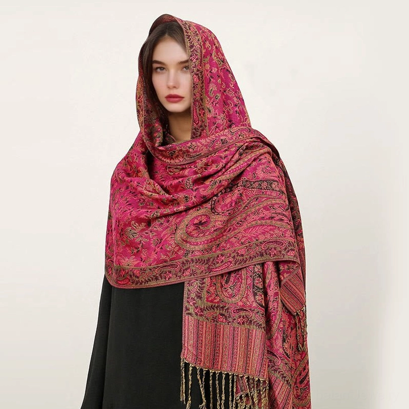 Model wearing rose red Tibetan paisley shawl with golden ethnic jacquard patterns and tassel hem, front headshot