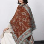 Tibetan paisley winter shawl worn on shoulders showing brown and blue floral pattern in home setting