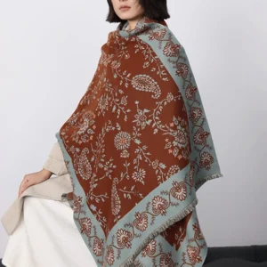 Tibetan paisley winter shawl worn on shoulders showing brown and blue floral pattern in home setting