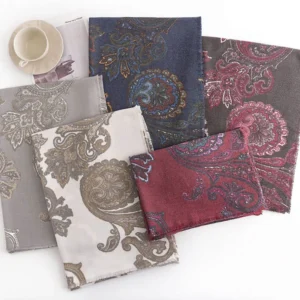 Multiple color variations of Tibetan paisley scarves arranged flat lay with coffee cup and magazine for styling inspiration