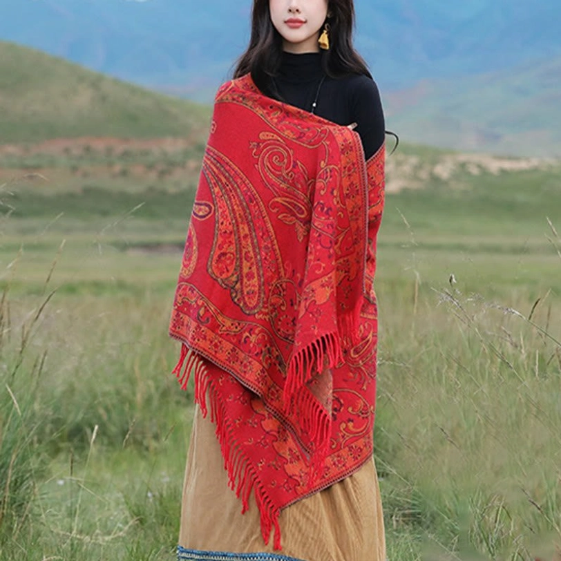 Red Tibetan tassel shawl worn on model showcasing warm burgundy paisley pattern and traditional fringe border