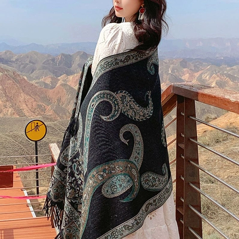 Tibetan teal paisley shawl side-back view on model at mountain overlook, displaying jacquard weave and draped fit