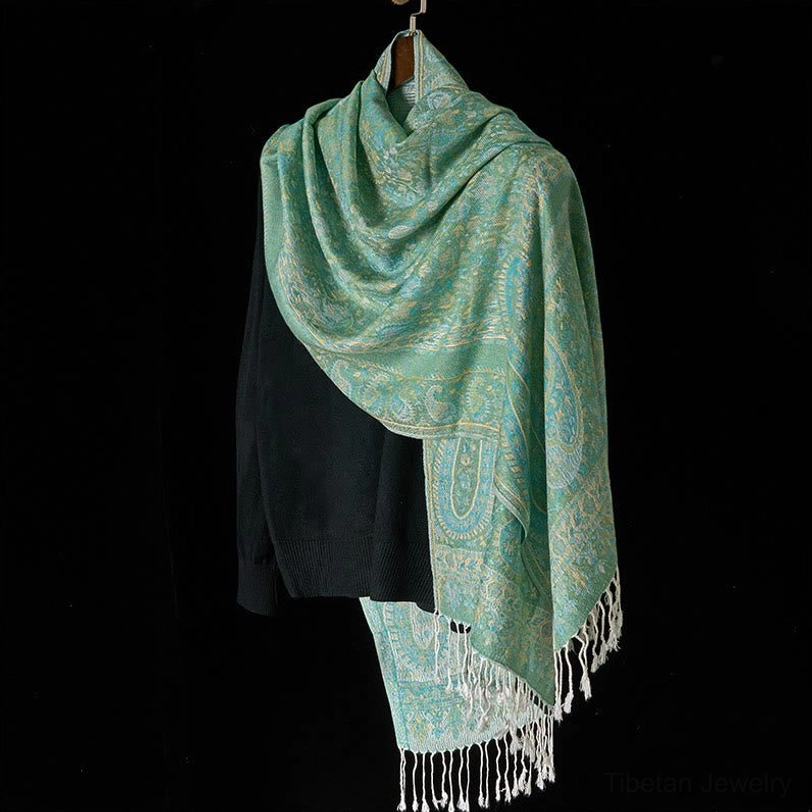 Pale teal Tibetan geometric paisley scarf with white tassel fringe, three-quarter side styling view