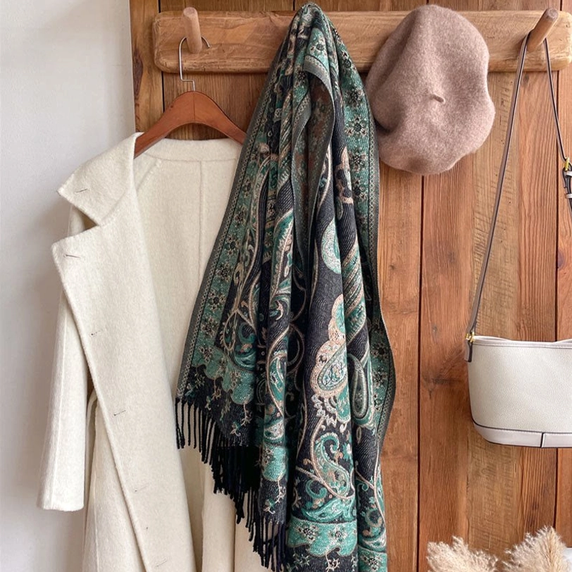 Tibetan paisley tassel shawl styled with white coat in home setting, highlighting teal pattern and versatile layering