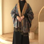 Woman wearing teal and mustard Tibetan paisley tassel shawl with contrast collar, full front view