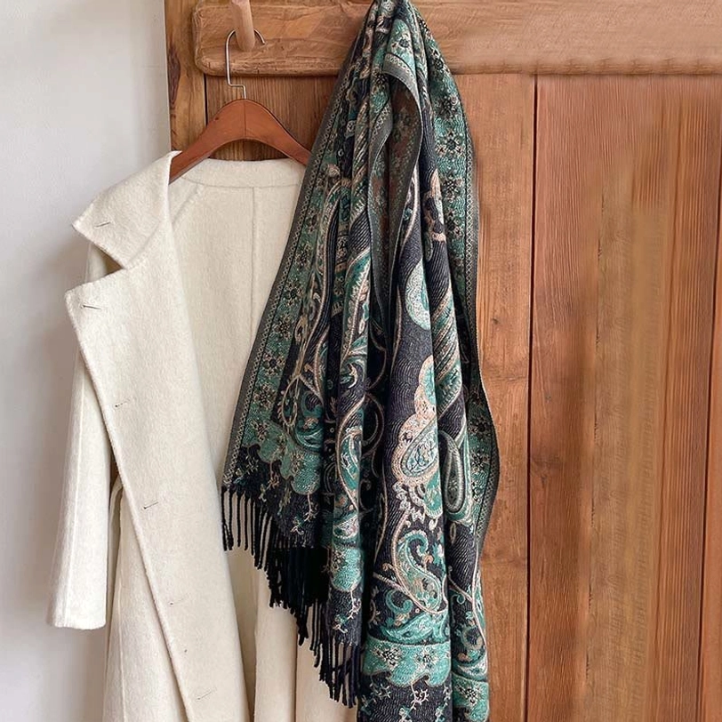 Tibetan paisley tassel shawl in teal design with black fringe, styled draped beside white overcoat