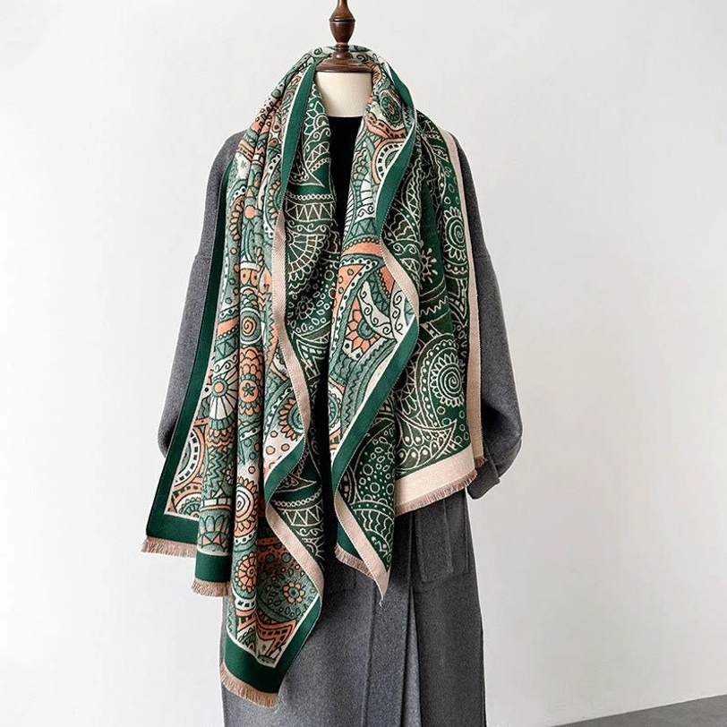 Tibetan paisley tassel shawl front view on dress mannequin paired with grey wool coat, featuring teal-dominant color scheme and fringed edges