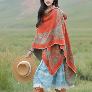 Dual-tone paisley print Tibetan wrap draped open-front style, right three-quarter view with alpine grassland backdrop