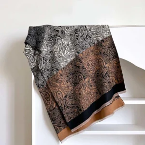 Tibetan winter wrap flat lay showing grey-brown color block paisley design with tassel hem on white shelf background