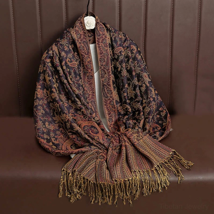 Navy Tibetan ethnic shawl with golden paisley jacquard hanging on brown leather sofa, front display with tassel hem