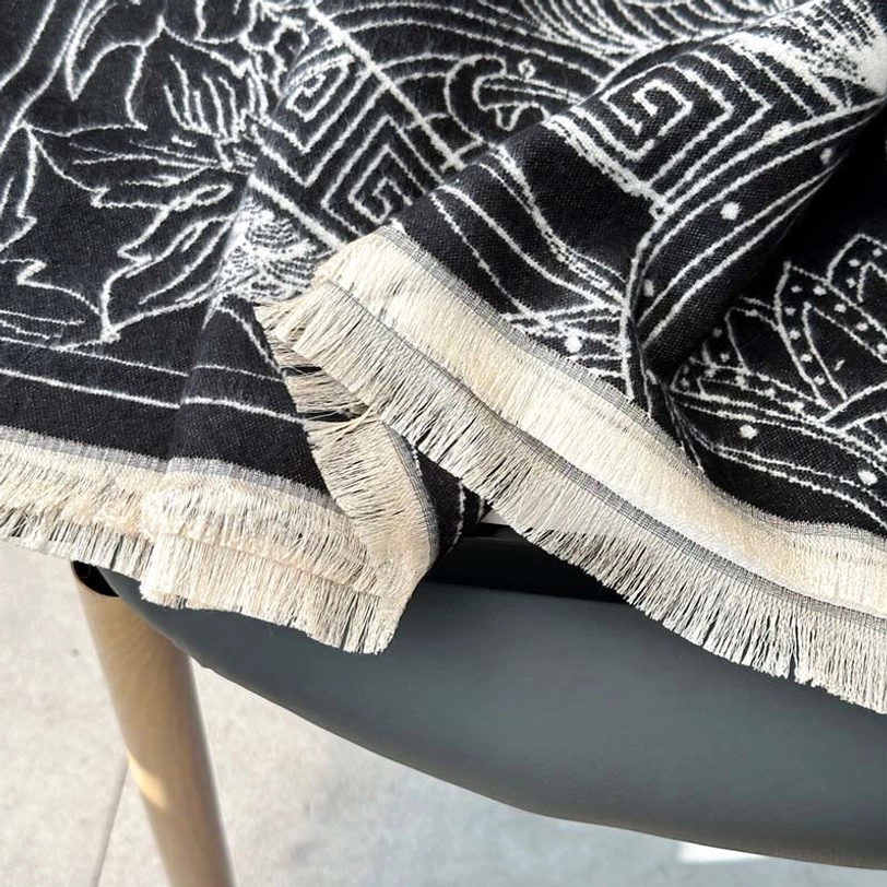 Close-up macro detail of Tibetan pavilion scarf showing woven fabric texture, thick off-white tassels, and precise pattern stitching