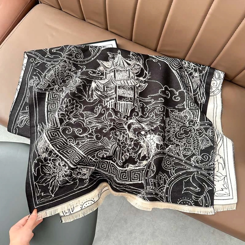 Side three-quarter view of Tibetan pavilion scarf held by hand showing intricate vintage woven pattern details on sofa background