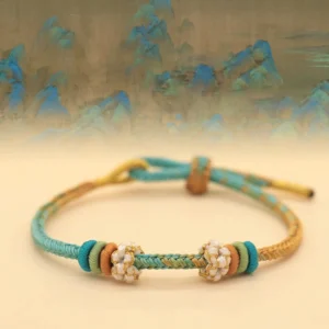 Handmade Tibetan eight-thread peace knot bracelet with teal, gold and brown woven design on ancient landscape background