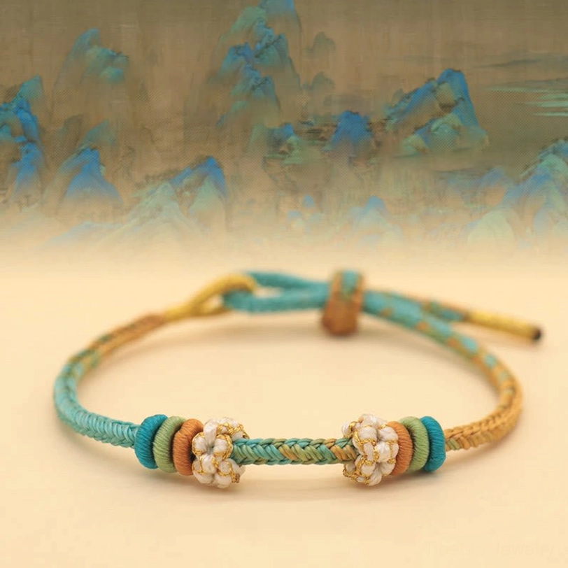 Handmade Tibetan eight-thread peace knot bracelet with teal, gold and brown woven design on ancient landscape background