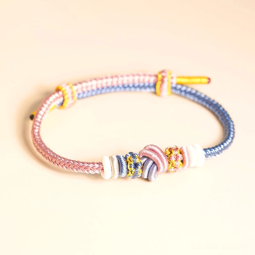 Pastel-toned Tibetan peace knot bracelet in pink and blue with white accents, featuring intricate woven knot ornamentation