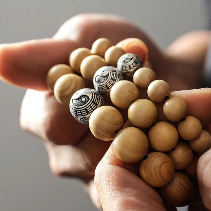 Tibetan peach wood bracelet with bagua silver spacer beads - hand held close-up on light background