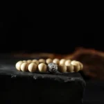 Tibetan peach wood bagua bracelet with yin yang symbol - top-down view of handcrafted wooden beads and engraved silver spacer on dark display