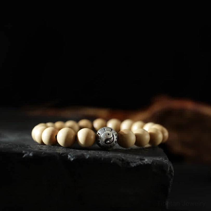 Tibetan peach wood bagua bracelet with yin yang symbol - top-down view of handcrafted wooden beads and engraved silver spacer on dark display