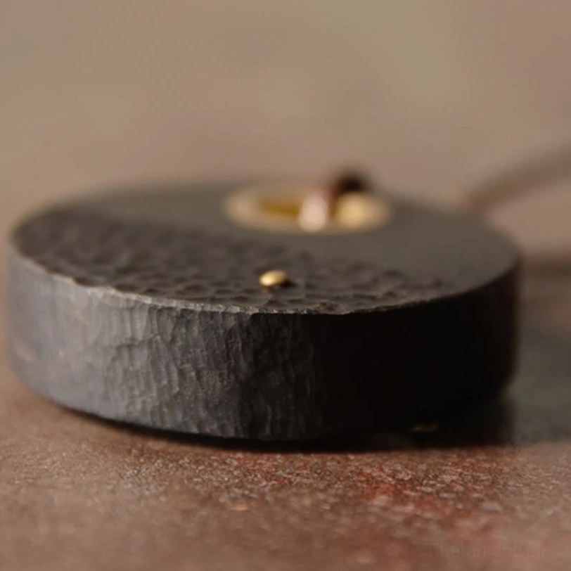 Close-up detailed view of ebony wood pendant front with brass inlay and decorative elements