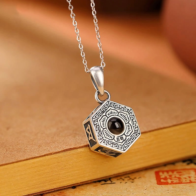 Tibetan mantra sterling silver pendant close-up front view featuring dark nano lens center with octagonal octagonal octagonal design and retro engravings on vintage background