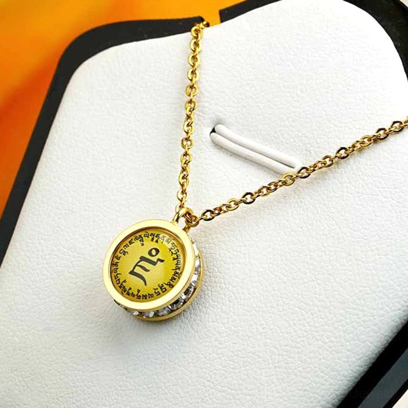 Tibetan Buddhist pendant necklace hanging on display with dainty gold chain and round yellow mantra design on white velvet