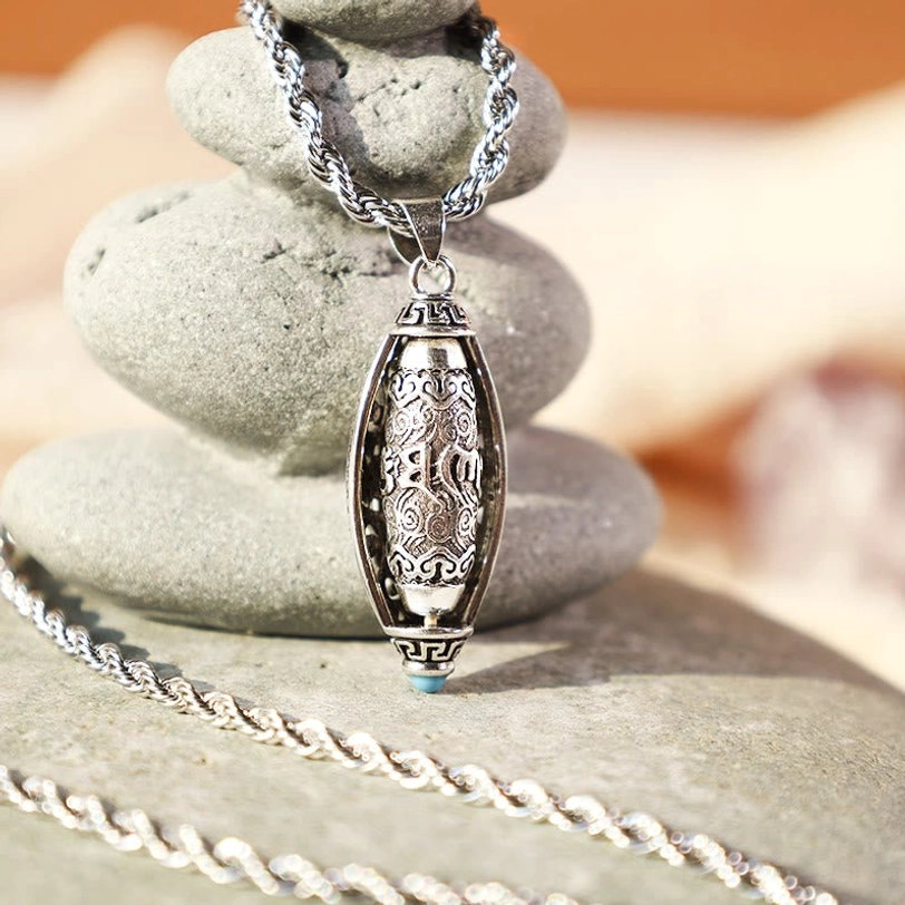 Tibetan mantra necklace side close-up displaying twisted silver chain and vintage pendant with blue accent on river stones