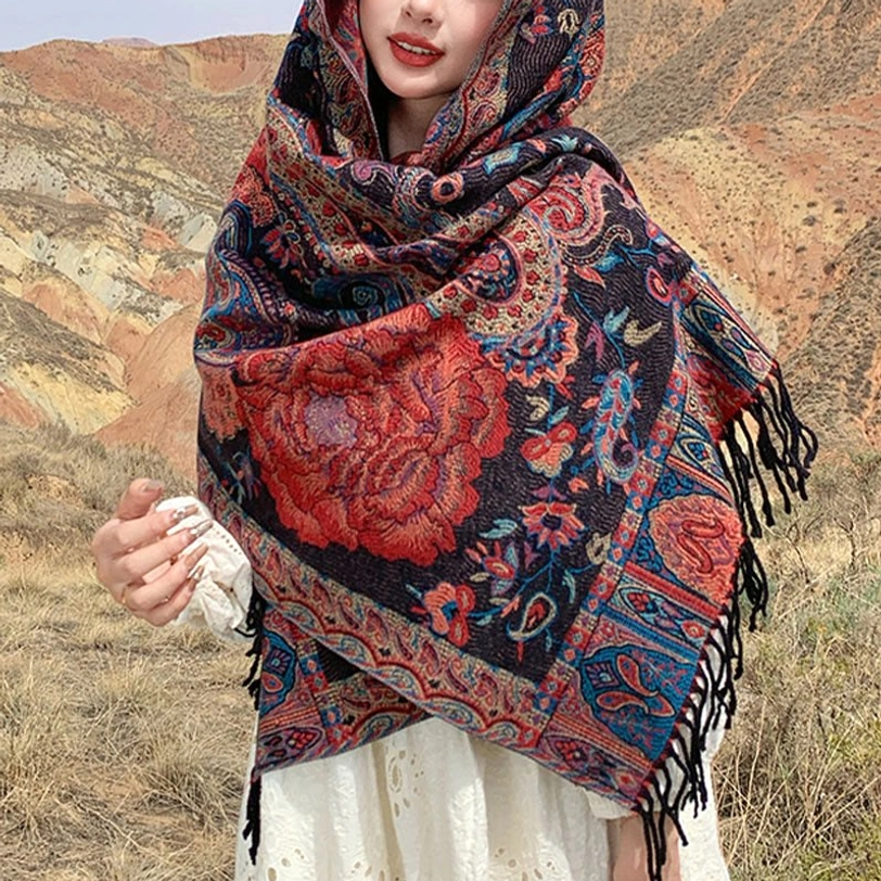 Hooded peony tassel shawl worn with white dress in outdoor grassland, bold red ethnic floral print front upper body view