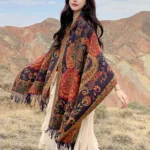 Tibetan peony tassel shawl worn over white dress in outdoor mountain landscape, full body view showcasing ethnic floral print and fringe detail