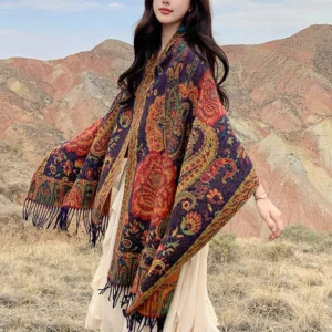 Tibetan peony tassel shawl worn over white dress in outdoor mountain landscape, full body view showcasing ethnic floral print and fringe detail