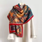 Tibetan phoenix peony scarf worn on shoulders with mannequin, showing red border trim and soft woven texture with tassel hem