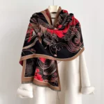 Tibetan phoenix flower tassel shawl worn as elegant black and red thermal wrap over white coat, showing frontal styling and cultural pattern details
