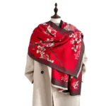 Red plum blossom Tibetan scarf with hand-printed floral pattern and tassel fringe worn on mannequin, front view