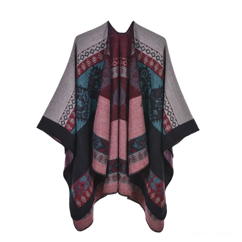 Tribal print poncho cloak rear close-up view showing full ethnic jacquard pattern and woven edge trim detail on grassland with resting cattle