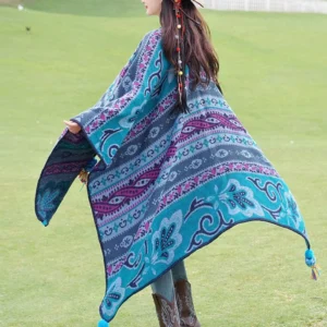 Tibetan geometric floral stripe poncho shawl back view in teal-purple with tassel hem, worn outdoors on grassland