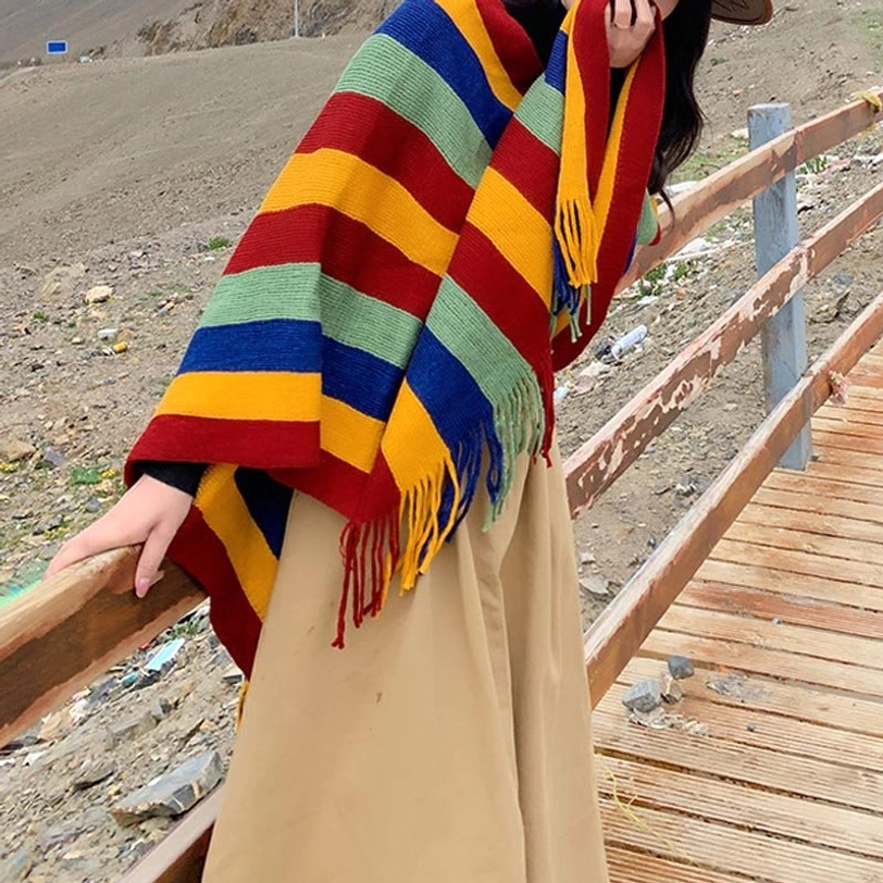 Tibetan poncho shawl worn at left side half-body view with visible shoulder tassels on wooden mountain road
