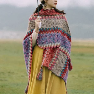 Red Pullover Tibetan ethnic poncho shawl with multi-color stripe weaving and tassel trims, front half-side view on grassland