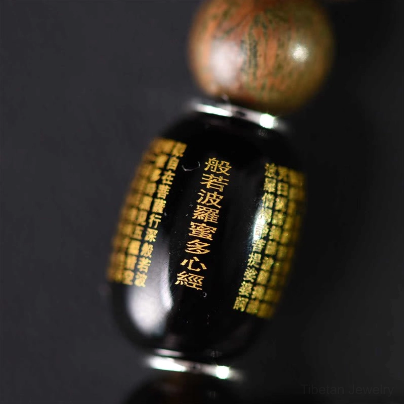 Engraved prayer bead with Buddhist sutra text topped with sandalwood bead macro shot
