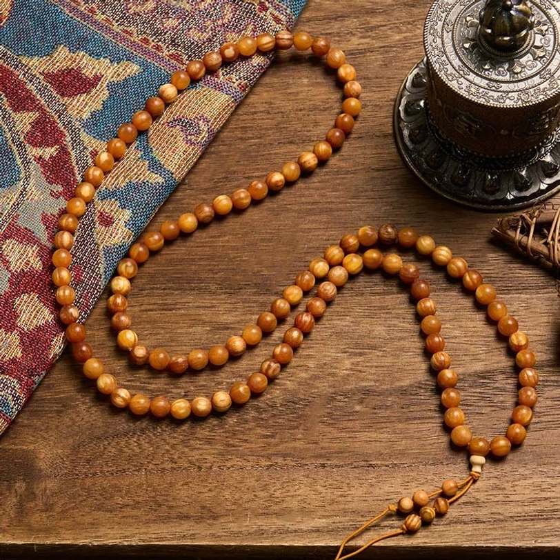 resin-rich pine wood prayer beads laid out flat showing uniform smooth wooden beads and extended strand design on ethnic tapestry