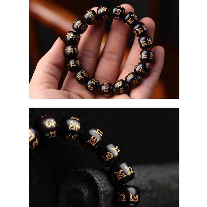 Hand-held Tibetan mantra prayer bracelet showing visible bead stringing holes and black ebony beads with hand-engraved gold Sanskrit text