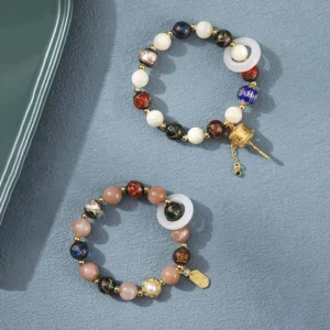 Two Tibetan spiritual bracelets featuring prayer wheels and mixed gemstone beads displayed together on gray surface