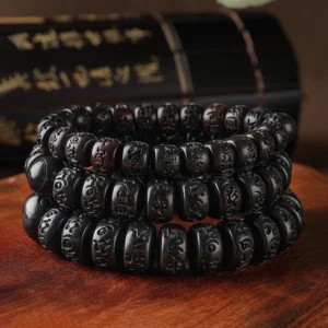 Multiple stacked Tibetan prayer bracelets displaying uniform dark wooden barrel beads with mantra carvings, high-angle arrangement on traditional backdrop