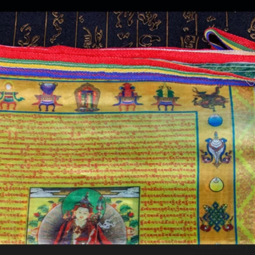 Close-up detail of Tibetan prayer flag showing Buddhist auspicious symbols, sutra text and central Buddha portrait