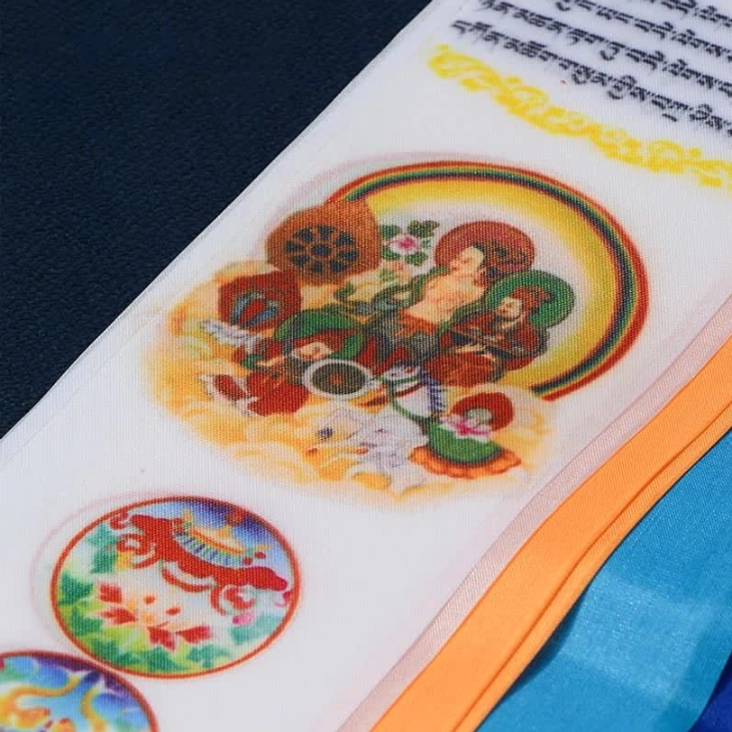Close-up detail of Tibetan prayer flag fabric showing Eight Auspicious Symbols, Buddhist deity prints and Tibetan sutra text