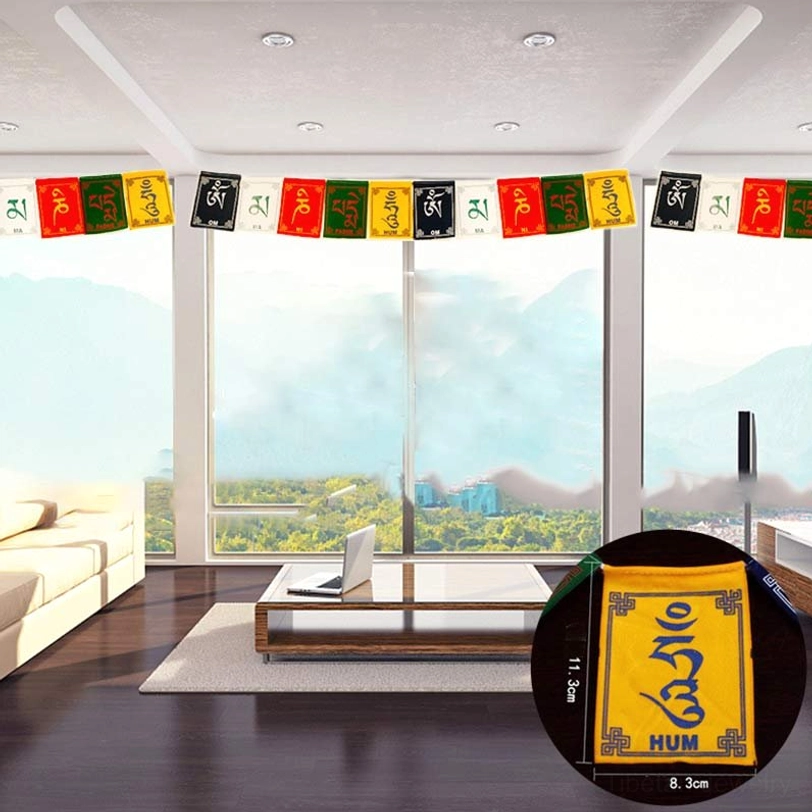 Tibetan prayer flag garland displayed indoors in modern living room with floor-to-ceiling windows, showing individual flag size reference