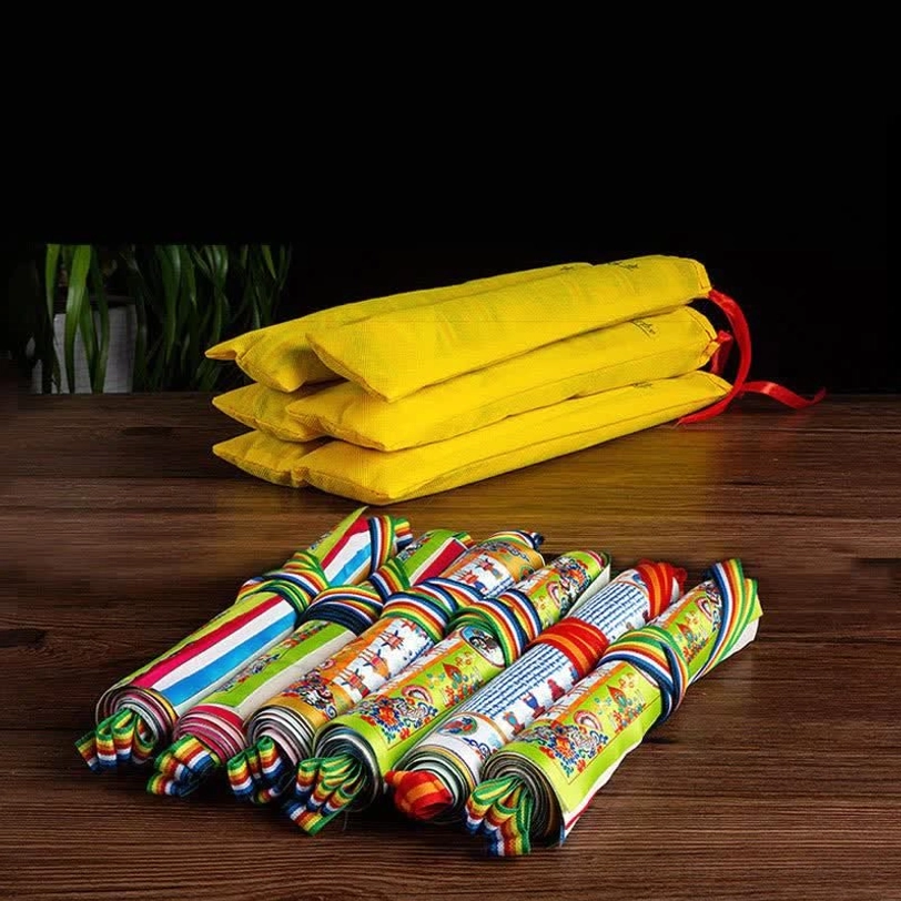 Stored Tibetan prayer flag set on wooden table, showing yellow fabric bundles and neatly rolled colorful 5-meter flag strings