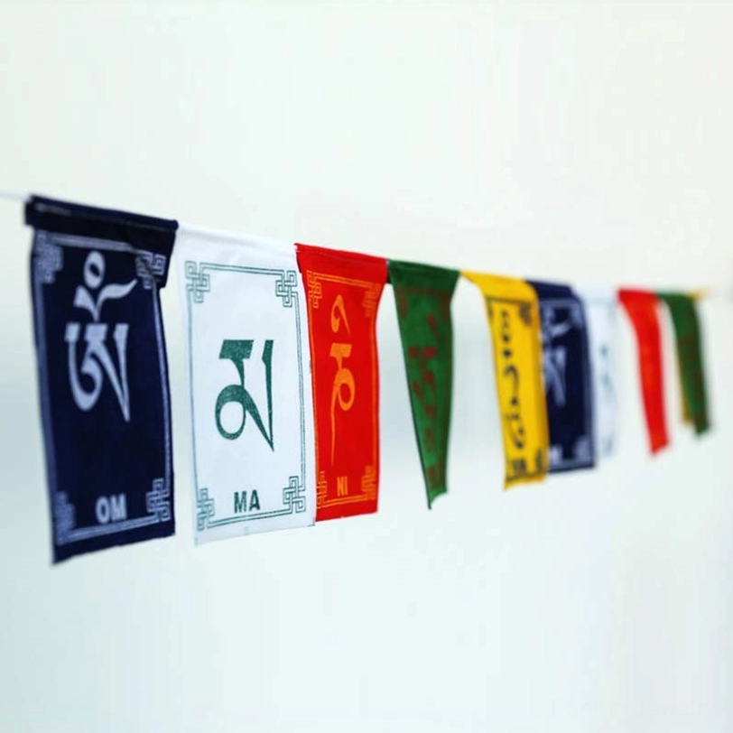 Vertical wall-hanging Tibetan prayer flag banner with colored sacred flags and clear traditional mantras indoors