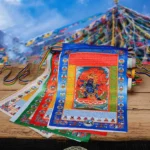 Tibetan windhorse prayer flag with vibrant multicolors displayed on snow mountain backdrop, showing intricate Buddha artwork and Tibetan scriptures in authentic outdoor setting