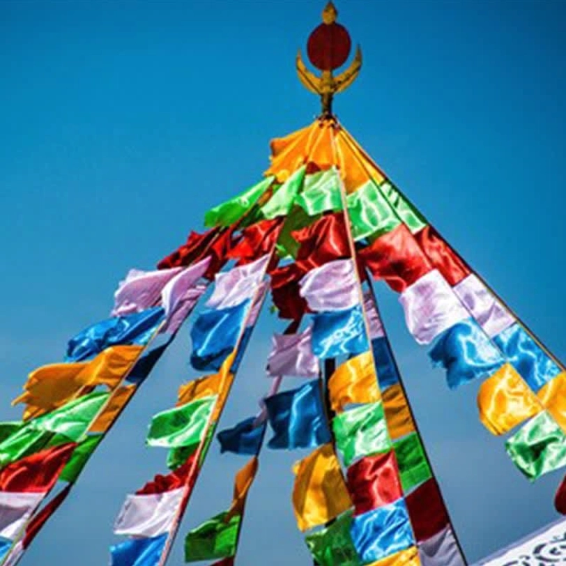 Tibetan 5-color windhorse prayer flags strung vertically outdoor against blue sky, traditional complete flag tower setup